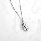 Silver necklace with a bean-shaped pendant on a light background