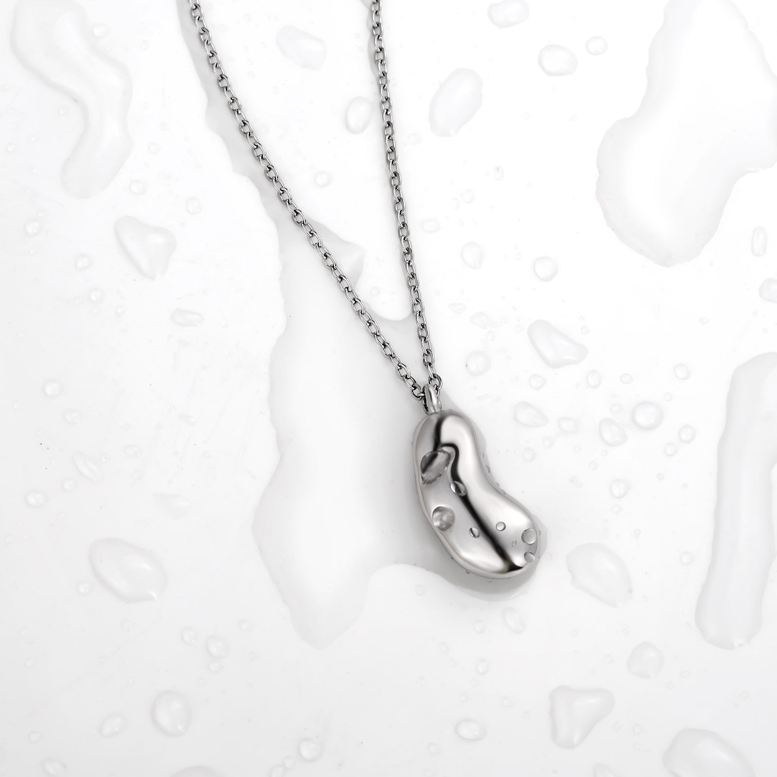 Silver necklace with a bean-shaped pendant on a light background